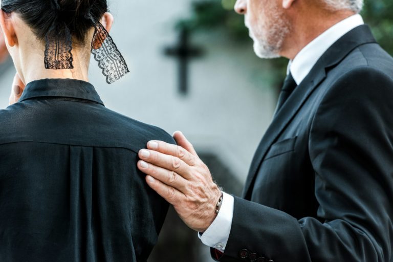 Gyászfeldolgozás és temetés szerepe cropped view of man touching woman on funeral