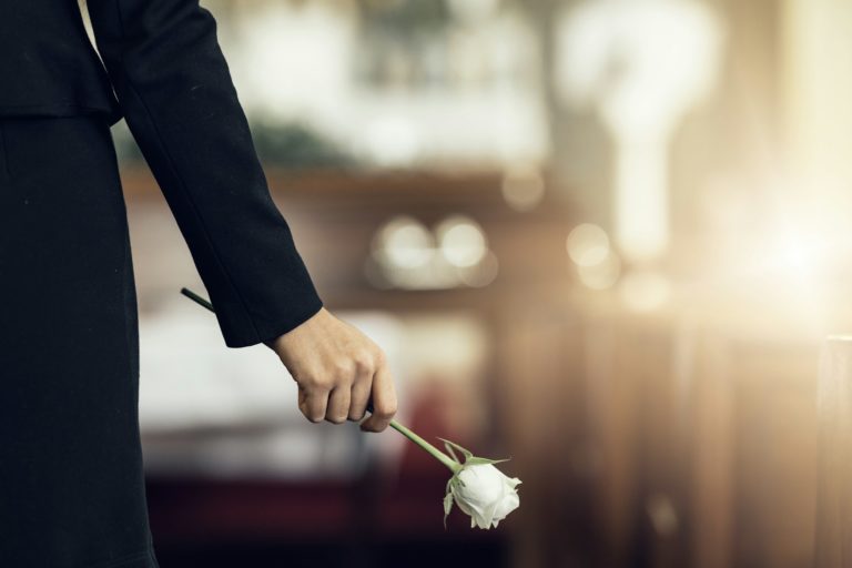 Hogyan beszélj egy gyászolóval? Mire ügyelj? Flower, funeral and hand holding rose in mourning at death ceremony with grief for loss burial. Flo