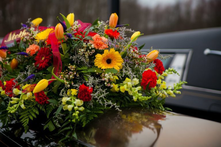Hasznos tanácsok temetés előtt: felkészülés, támogatás Funeral Casket and flowers next to hearse