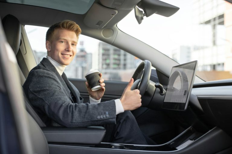 Az autonómia fogalma: függetlenség vagy önmeghatározás? Handsome smiling Caucasian business man riding autonomous car, drinking coffee to go