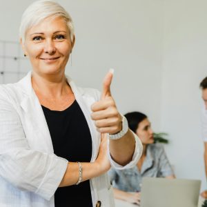 Confident stylish European mature middle aged business woman leader with thumbs up