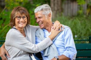 older loving couple sitting outside on park bench