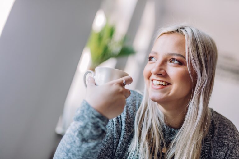Martin Seligman: Pozitív pszichológia és life coaching Positive woman holding cup in office