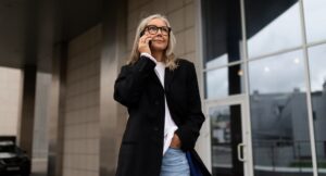 an elderly business woman enters the office center talking on a mobile phone, woman leader in