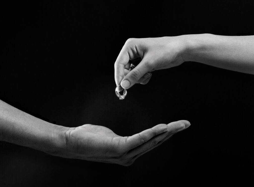 couples hands breaking up - wedding ring