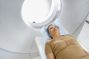 Female patient lying on table and entering CT machine during examination procedure in hospital