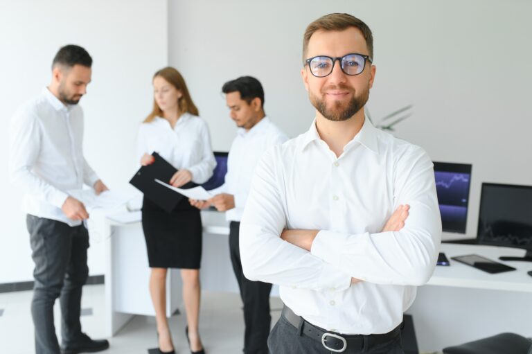 Stratégiai karizmacoaching – A felsővezetői jelenlét Team leader stands with coworkers in background