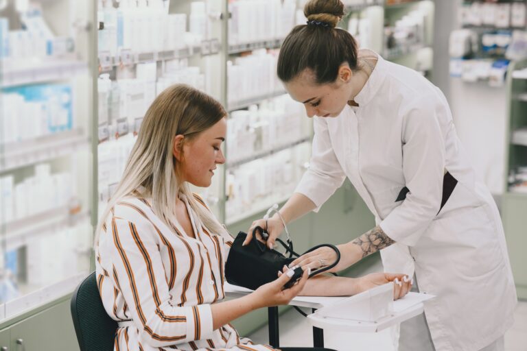 Magas vérnyomás-betegség a vállalkozók körében Trainee taking blood pressure of his customer in the pharmacy