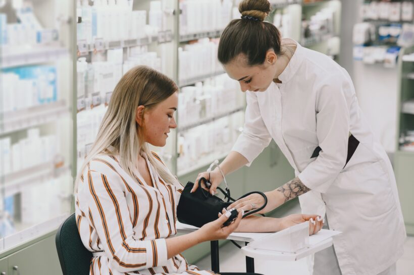 Trainee taking blood pressure of his customer in the pharmacy