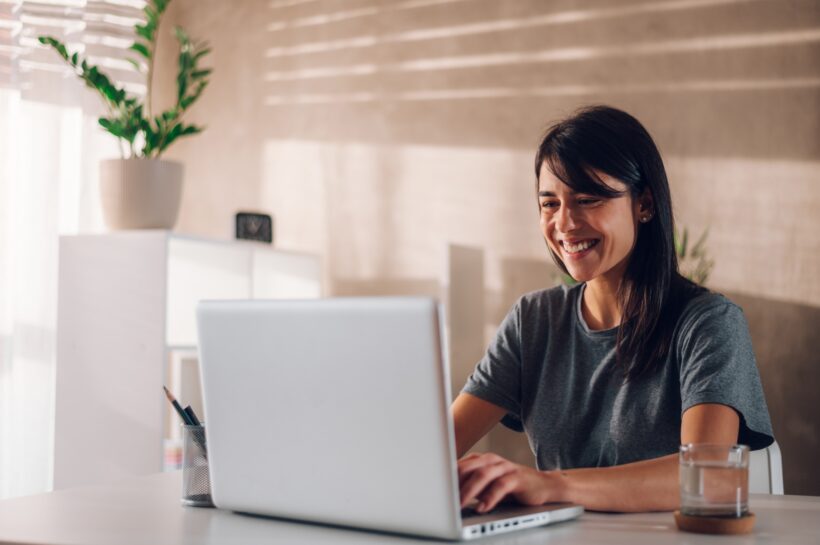 Happy female team leader hosting an online meeting while using her laptop.