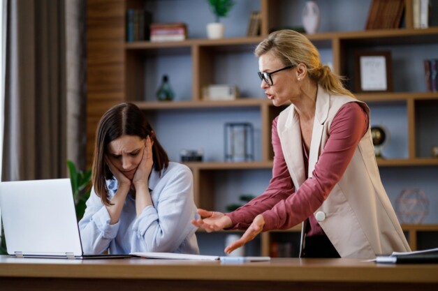 Angry female boss scolding scared office worker. Demanding manager leader is annoyed at laziness and