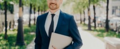 Businessman in suit walking on street holding laptop