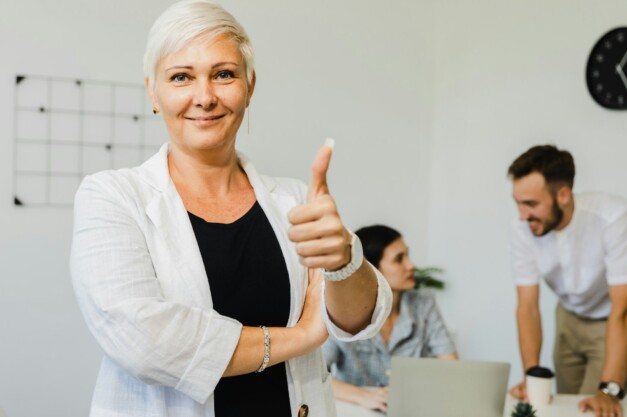 Confident stylish European mature middle aged business woman leader with thumbs up