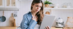 Confused pretty caucasian woman makes video call uses tablet touches chest feels frustration unhappy