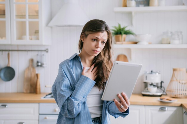 Confused pretty caucasian woman makes video call uses tablet touches chest feels frustration unhappy