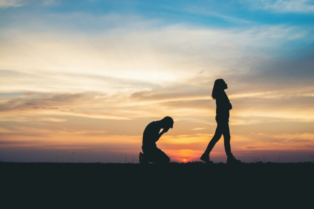 Couple silhouette breaking up a relation on the road at sunset.