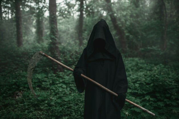 Death in a black hoodie with a scythe in forest