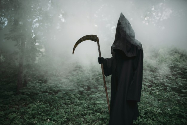 Death with a scythe in the dark misty forest