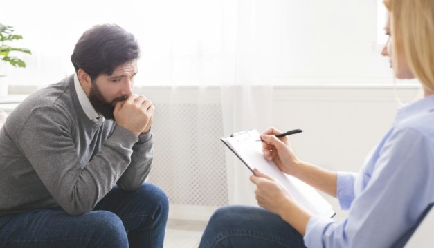 Depressed man getting psychological treatment at office