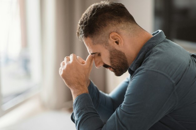 Depressed middle aged man grapples with grief sitting at home