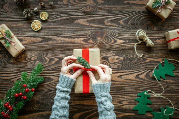 Hands decorating a Christmas gift box