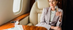 happy businesswoman holding champagne glass in private plane