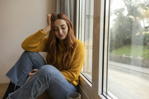 Sad woman drinking wine. Young redhead woman drinking wine at home