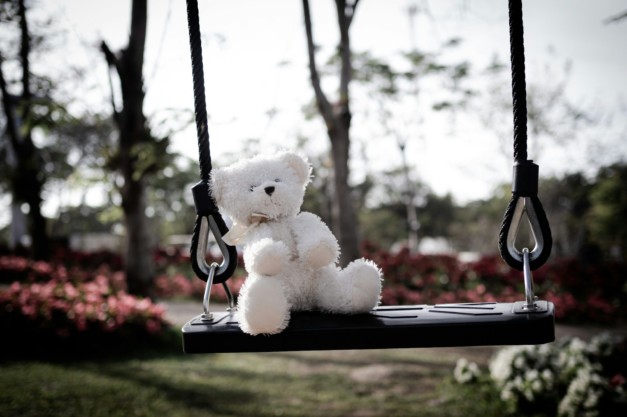 Teddy Bear sitting on Swing, Symbols Violence Domestic Abuse Sad grief