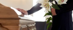 woman with lily flowers and coffin at funeral