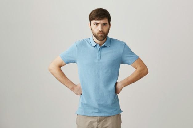 You will be punished. Studio shot of angry cute caucasian guy with beard and moustache holding hands